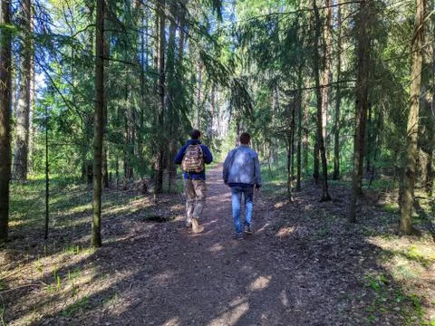 Two young men confidently walking in the park in the daytime. Rear view photo Photos