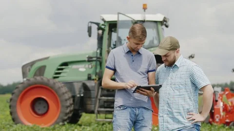 Two young men of the farmer communicate, use the tablet. Stand in the field Stock Footage 77334401