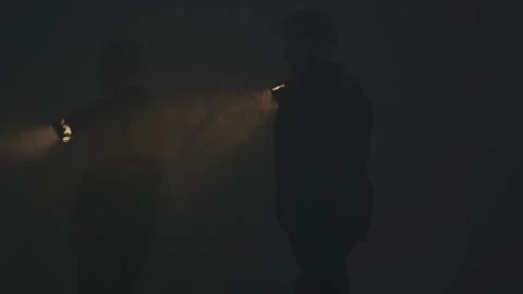 Two young men with flashlights searching something in foggy darkness. Close-up Stock Footage 246869202