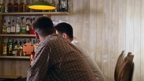 Two young men friends sitting in bar and talking with each other while drinking Vídeos de archivo 83203912