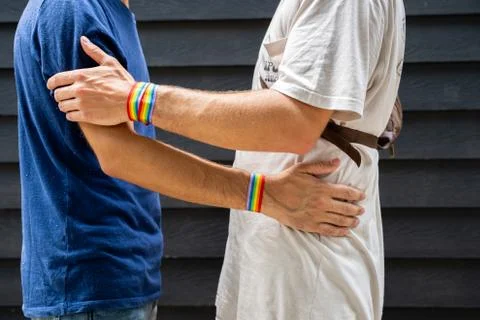 Two young men hugging each other with an lgtb flag bracelet on the street Stock Photos