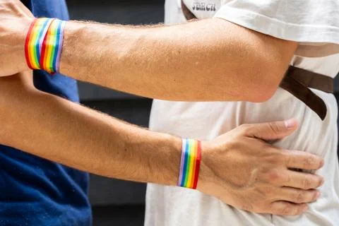 Two young men hugging each other with an lgtb flag bracelet on the street Stock Photos