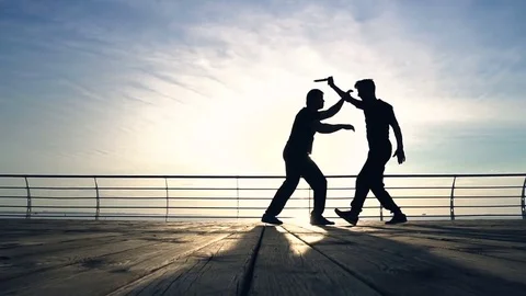 Two young men with knife fight training against sunrise in slow motion Stock Footage 77718805