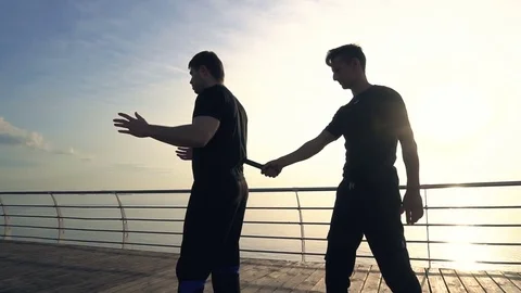 Two young men with knife fight training against sunrise in slow motion Stock Footage 77720057