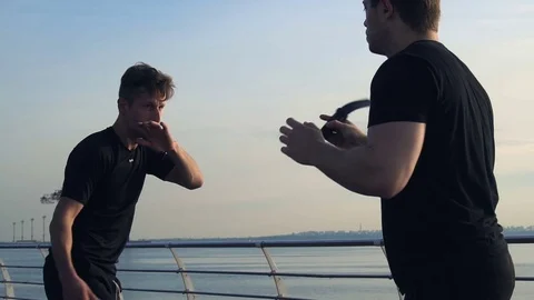 Two young men with knife fight training against sunrise in slow motion Stock Footage 77723561