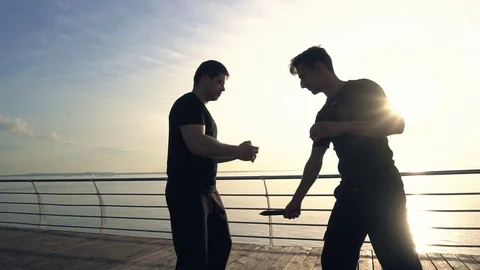 Two young men with knife fight training against sunrise in slow motion Video stock 77831375