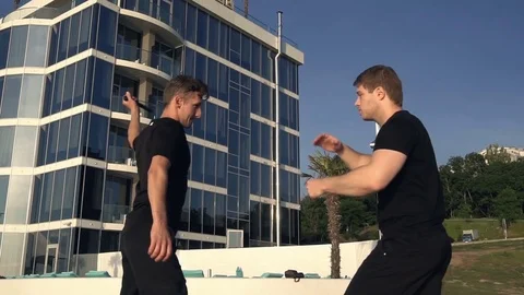 Two young men with knife fight training against sunrise in slow motion Stock Footage