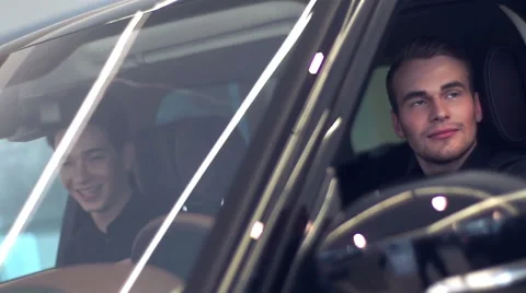Two young men laughing in car salon Stock Footage 64375595