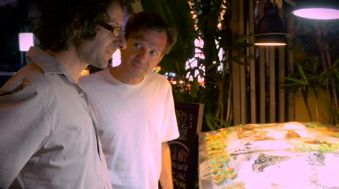 Two young men look at fresh fish in a restaurant together Stock Footage 55448688