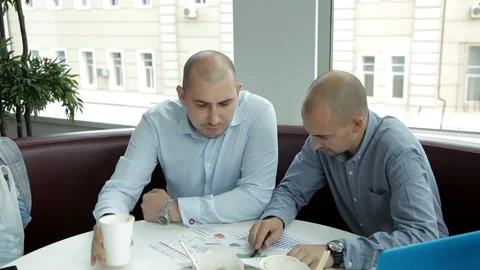 Two young men at lunch in a cafe drinking coffee and eating noodles discussing Stock-Footage 95448685