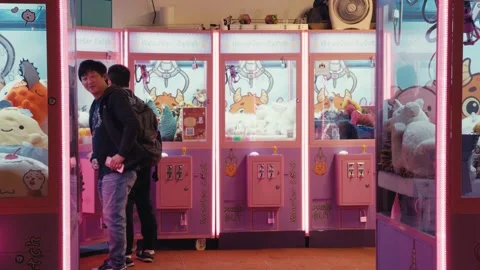 Two young men at monster catch claw machines with plush toys Stock Footage 334022077