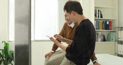 Two young men in the office talking over a tablet pc Stock Footage 100958279