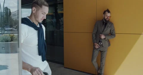 Two young men, one dressed in classic one in casual in the city mall Stock Footage 142462786