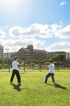 Two young men performing martial arts forms in a city park Stock Photos