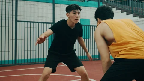 Two young men play intense basketball on an outdoor court with one dribbling Vídeos de archivo 347334325