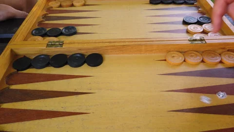 Two young men playing backgammon on a wooden table rolling dices. Video stock 136774765