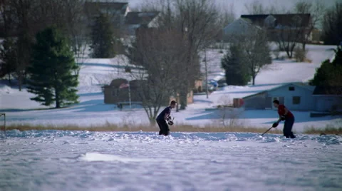 Two young men playing ice hockey on a snowy field Stock Footage 59547572