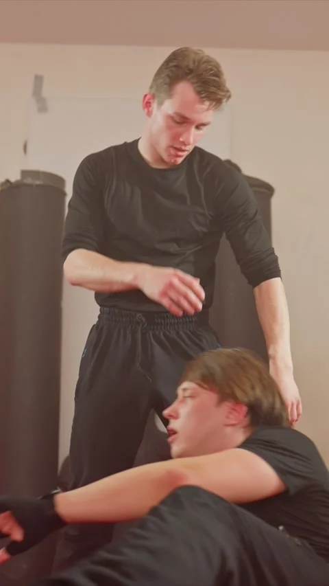 Two young men practice martial arts techniques on red mat with close ups of arm Stock Footage 343083291