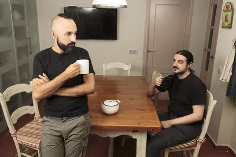 Two young men quietly drinking a hot beverage together Stock Photos
