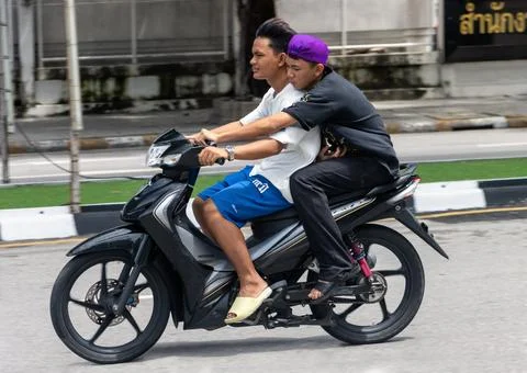 Two young men ride a motorcycle in the city Stock Photos