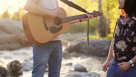 Two young men singing, playing guitar and spending weekend outdoors in the Stock Footage 76010581