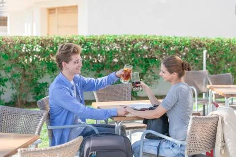 Two young men sit holding hands as they look at each other in a smiling manne Stock Photos