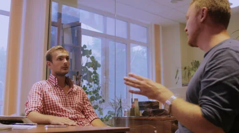 Two young men sit at office and discuss the plan of future project Stock Footage 58016464