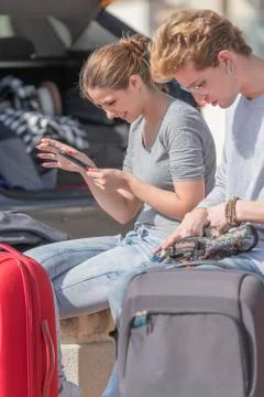 Two young men sit while she smilingly checks her phone while he checks a kang Stock Photos