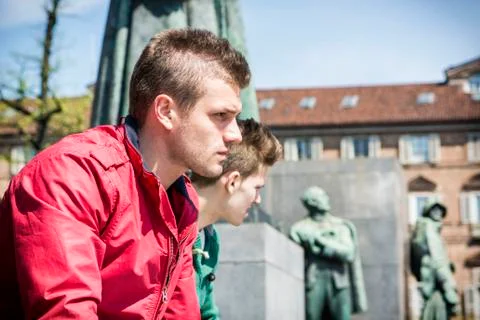 Two young men sitting on low wall in urban setting Stock-Fotos