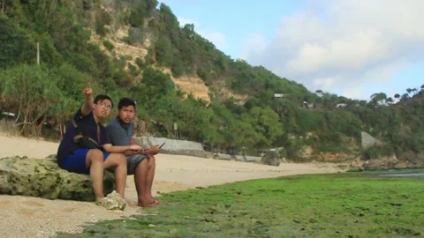 Two young men sitting on a rock Video stock 275462911