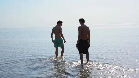 Two young men slowly enter the water. handheld shooting 스톡 동영상 90805827