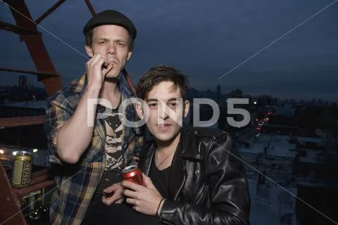 Two young men standing on a fire escape at night Stock Photos