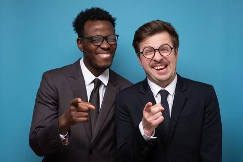 Two young men in suits posing with folded arms and smiling to the camera. Stock Photos