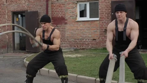 Two young men train and do different exercises with battle ropes while standing Vidéo 130176894