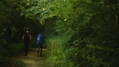 Two young men walk through an English park. Stockbeeldmateriaal 135483576