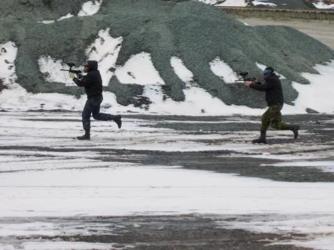 Two young men with weapons run to the attack. Playing Paintball. Extreme sport Foto stock
