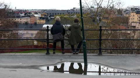 Two young Millennial boys sitting together talking and looking at the city Stock Footage 62869704