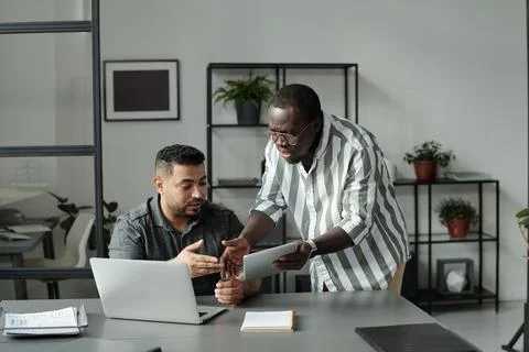 Two young multicultural colleagues with mobile gadgets arguing about data Stock Photos