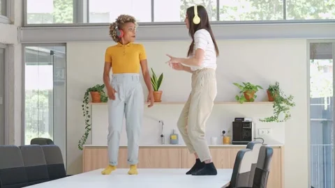 Two young multiethnic women dancing on top of an office or coworking table. Stock Footage 158748221