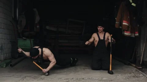 Two young muscular men train and do push-ups based on large sledgehammers and Video stock 130177406