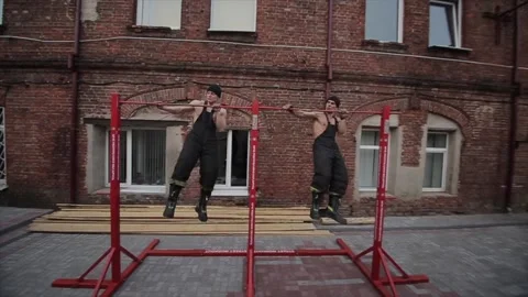 Two young muscular men train and do extreme push-ups on the horizontal bar from Stock-Footage 130178009