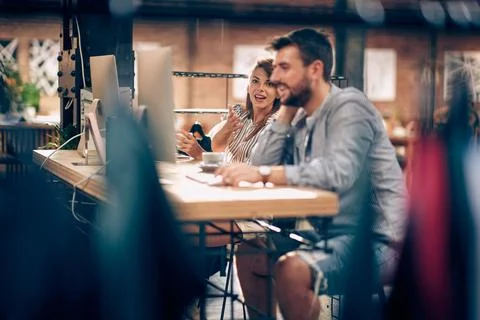 Two young office workers in casual clothes chatting on coffee break, sittin.. Stock Photos