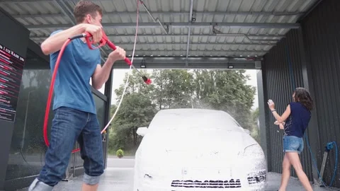 Two young people are strengthening their relationship by washing a car outside Stock Footage 280307662