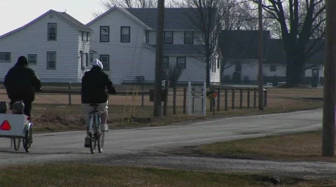 Two young people on bikes pull two very young kids in a child carrier Stock Footage 439499
