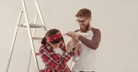 Two young people have fun preparing for repairs in new apartment. Man playfully Stock Footage 144629754