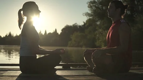 Two young people meditating on a dock 動画素材 76223489