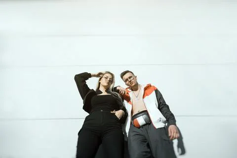 Two young people posing on a white wall, modern urban couple concept Stock Photos