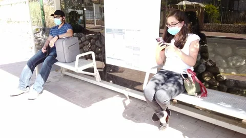 Two young people with protective masks, waiting for the bus Stock Footage 133842428