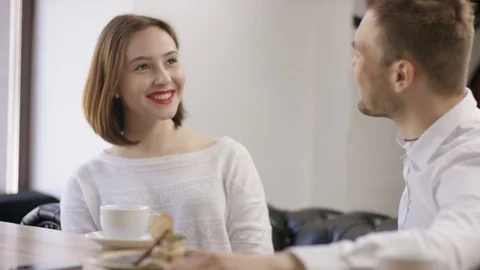 Two young people is sitting in a cafe. Man and woman are smiling and sitting in Stock Footage 94472948