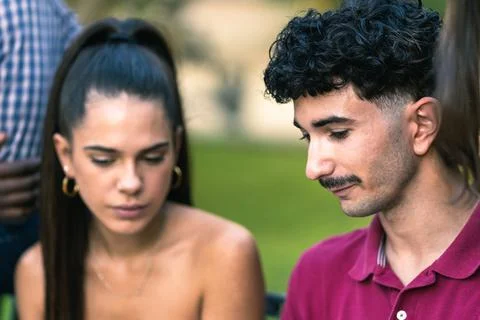 Two young people talking surrounded by other people in a park Stock Photos